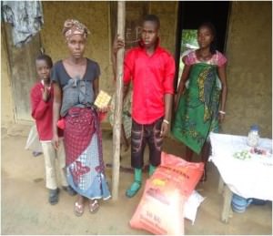 Four member of a family stand outside their home in Sierra Leone with a sack of rice and other food supplies they have just received.